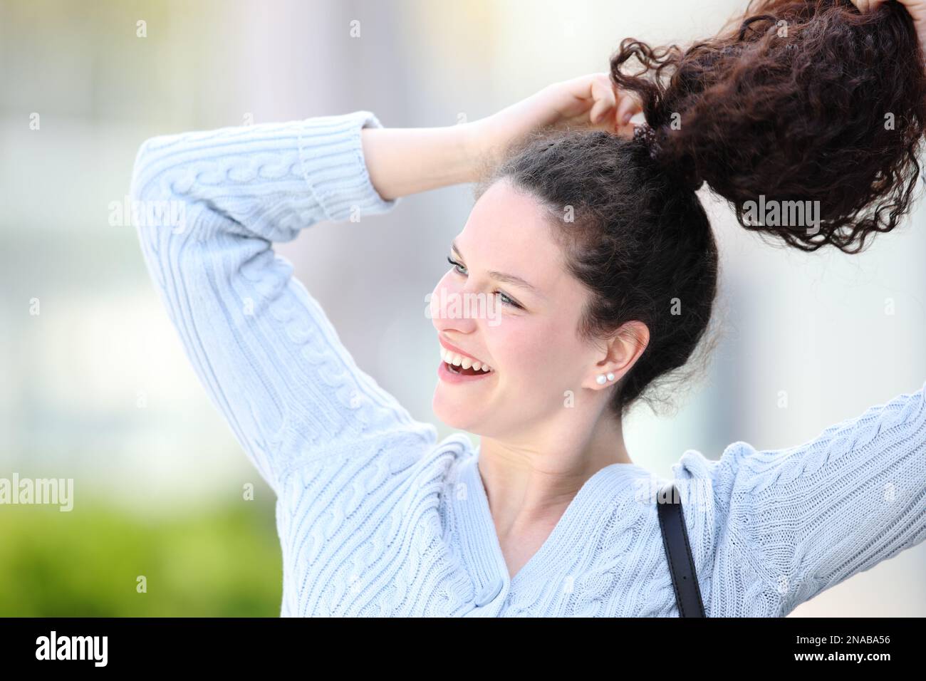 Happy lady making ponytail outdoors in the street Stock Photo