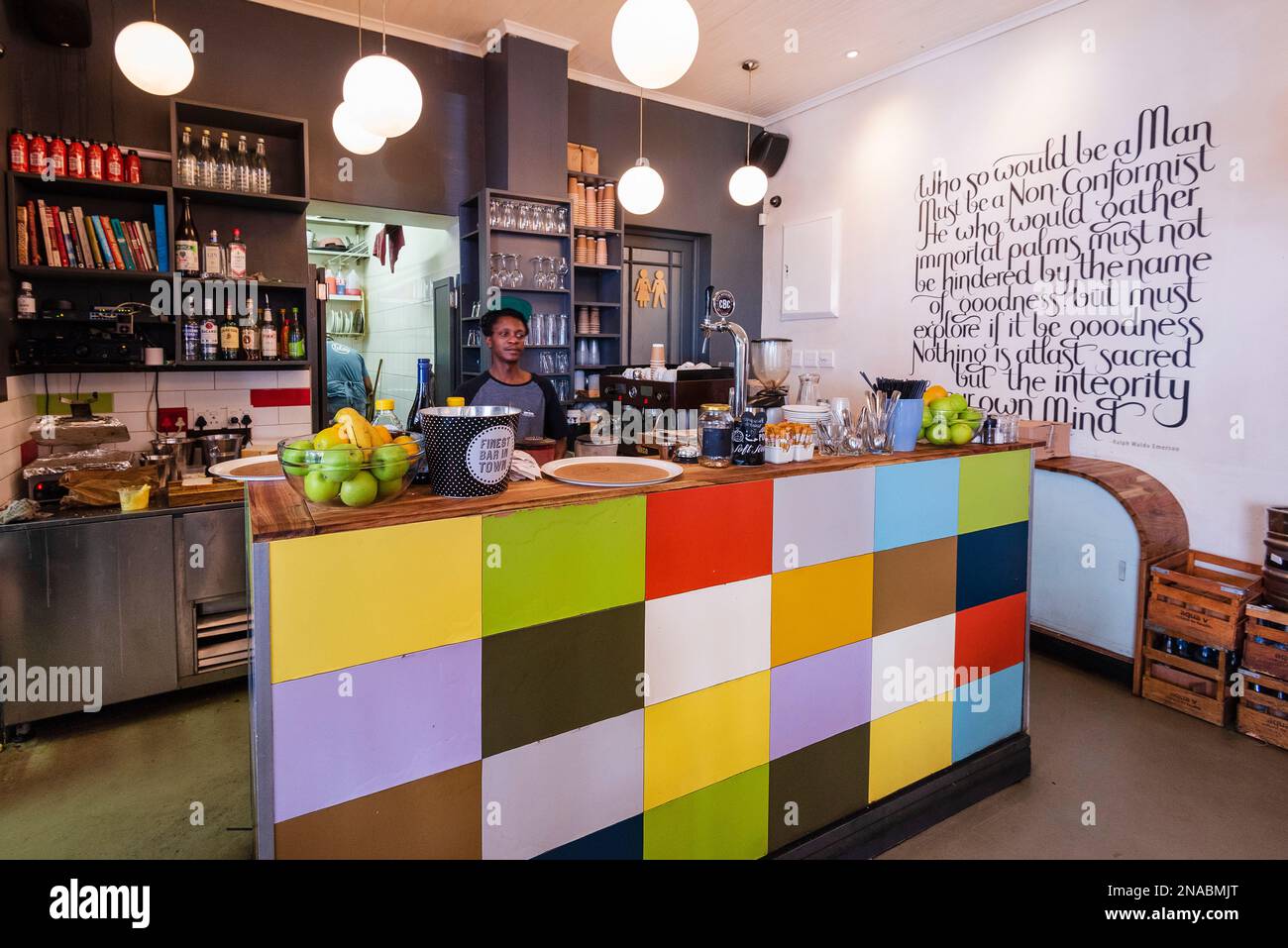 Worker behind a colourful counter in a restaurant; Cape Town, South Africa Stock Photo