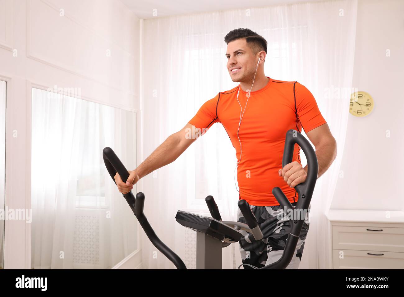 Using Elliptical Machines Man using modern elliptical machine at home Stock Photo - Alamy