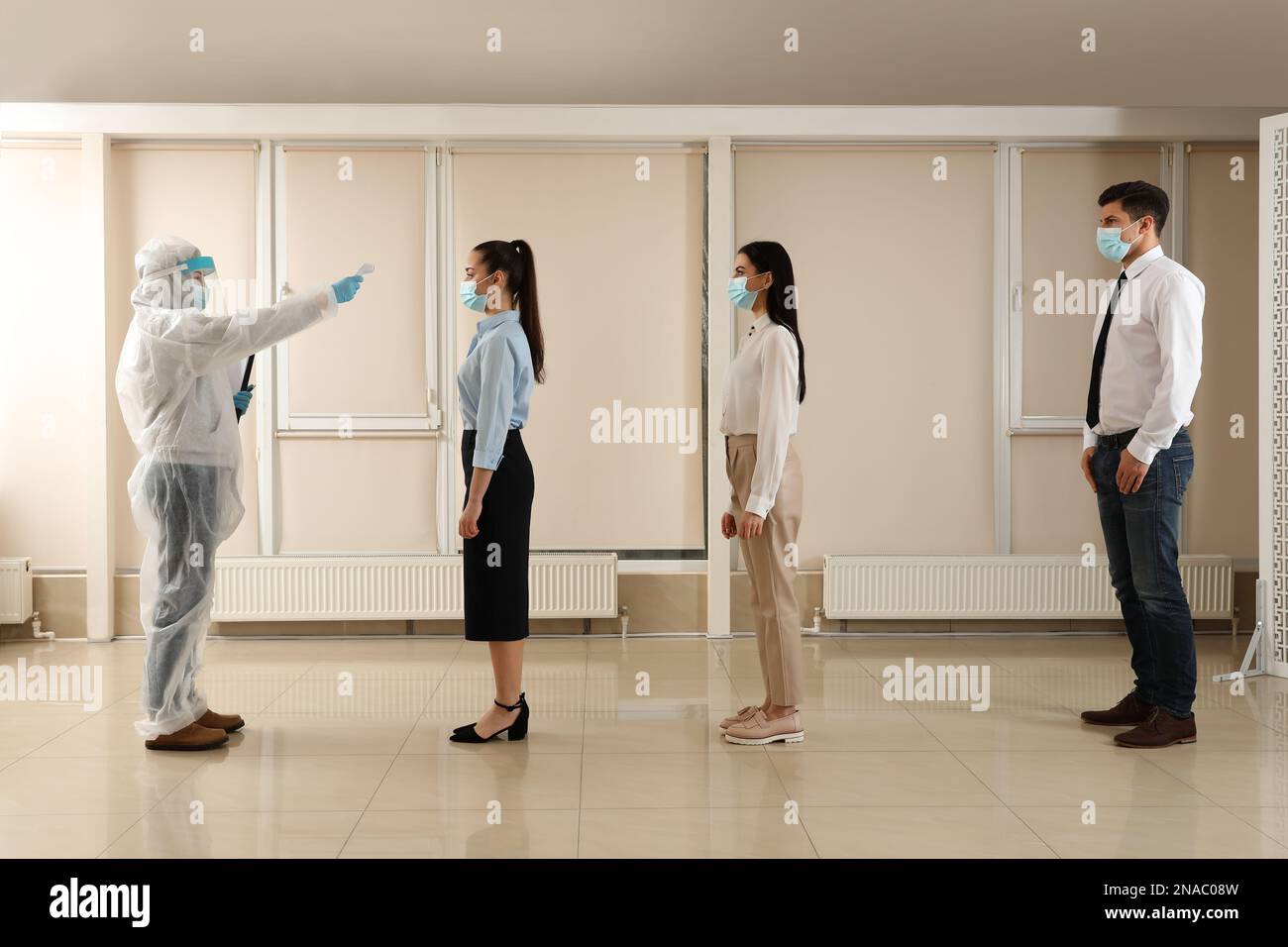 Doctor measuring employees temperature in office. Prevent spreading of ...