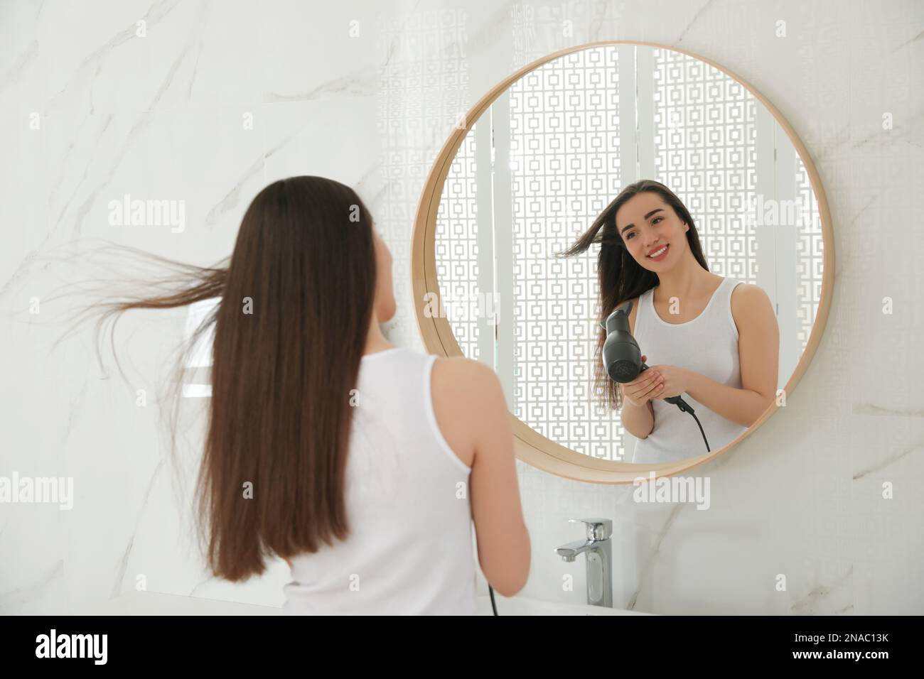 Beautiful young woman using hairdryer in bathroom Stock Photo Alamy