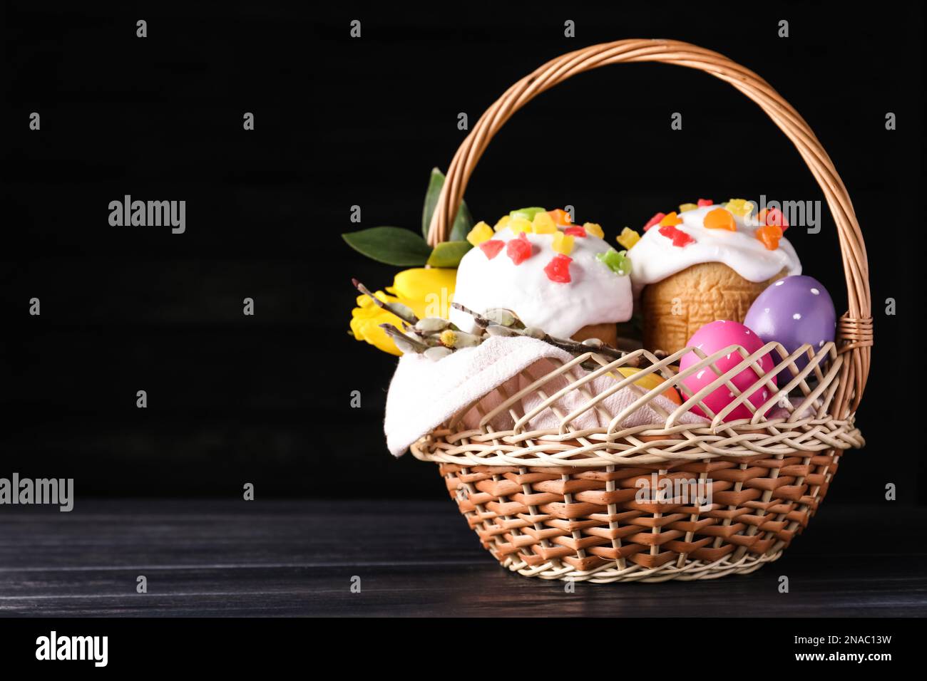 Traditional Easter cakes in wicker basket on dark background. Space for text Stock Photo