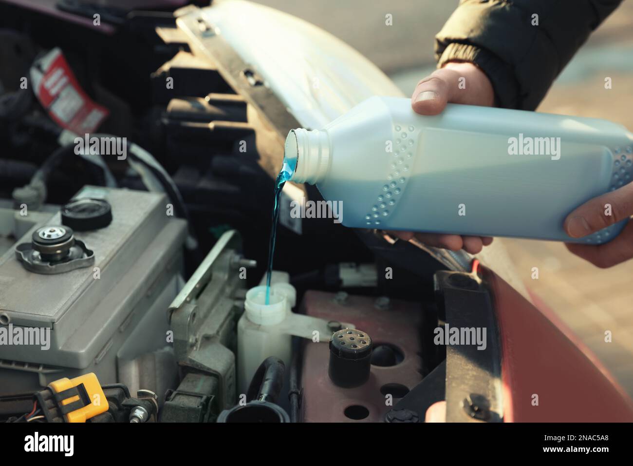 Man filling car radiator with antifreeze outdoors, closeup Stock Photo