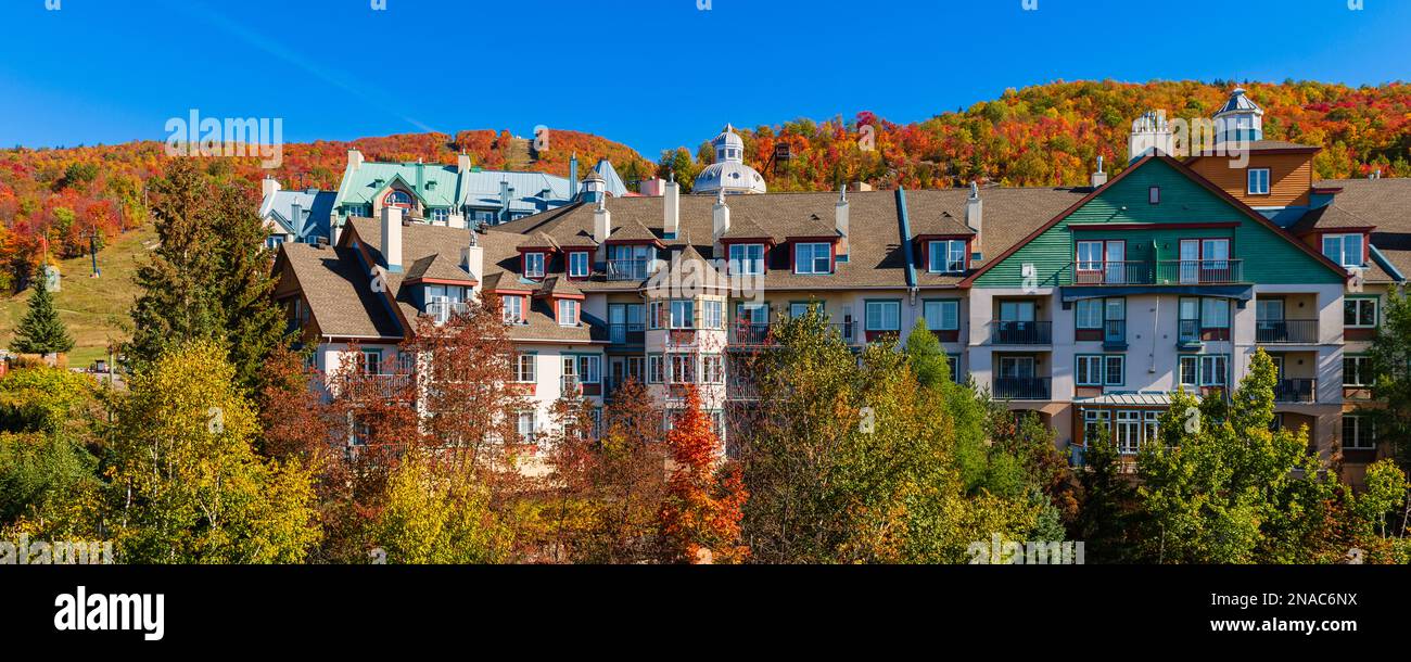 Vibrant autumn colours cover the hills around the residential buildings in the Laurentides of Mont-Tremblant, Quebec;  Mont-Tremblant, Quebec, Canada Stock Photo