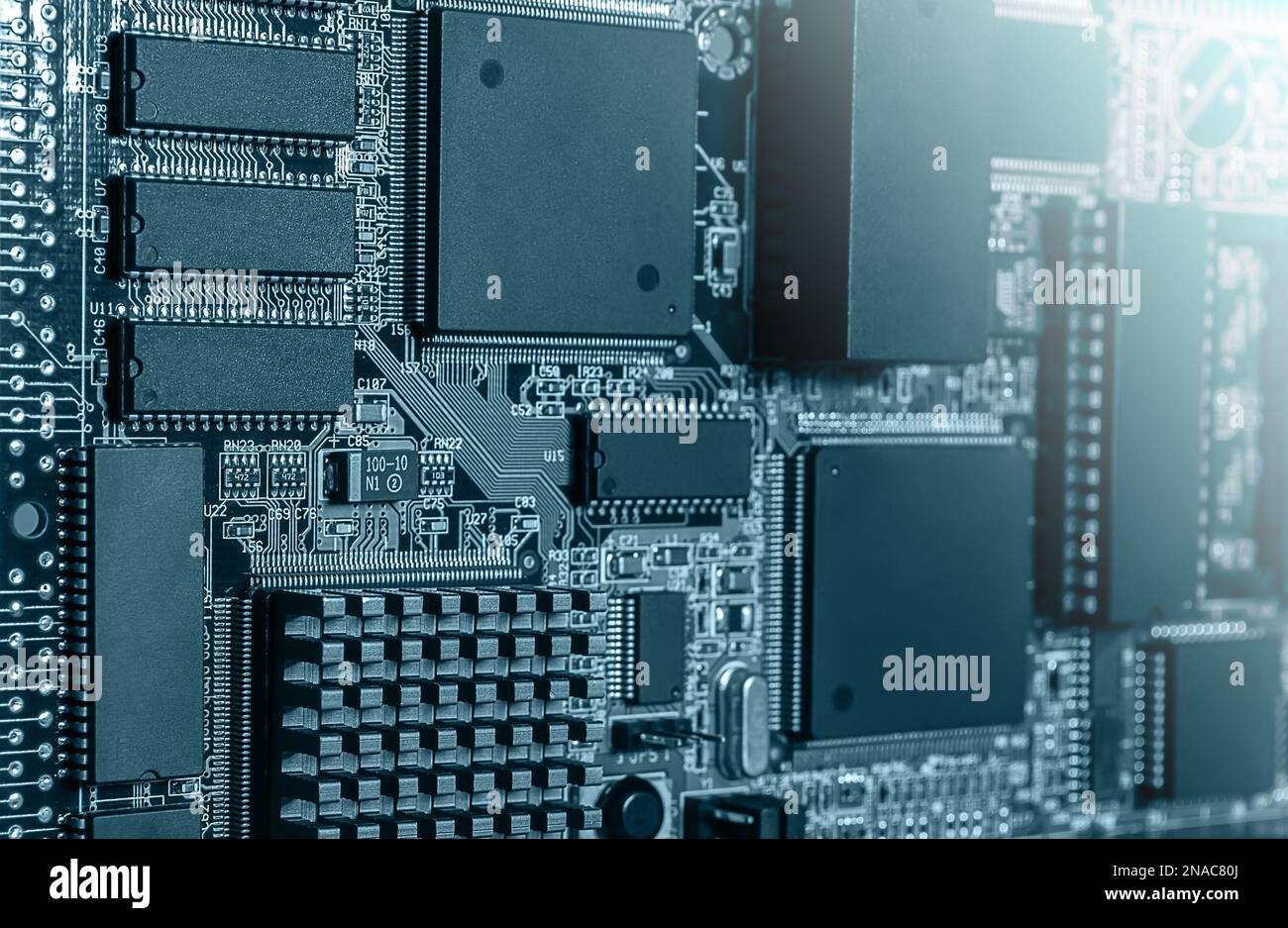 Closeup of Printed Circuit Board with processor, integrated circuits and many other surface mounted passive electrical components. Stock Photo