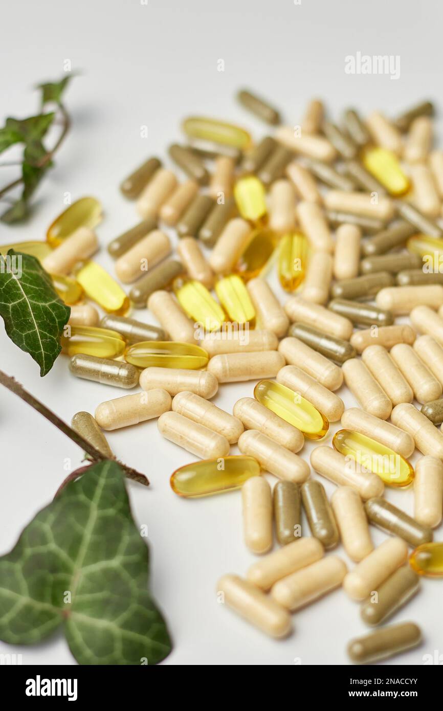 Pills, medical tablets with green plants, leaves on white background