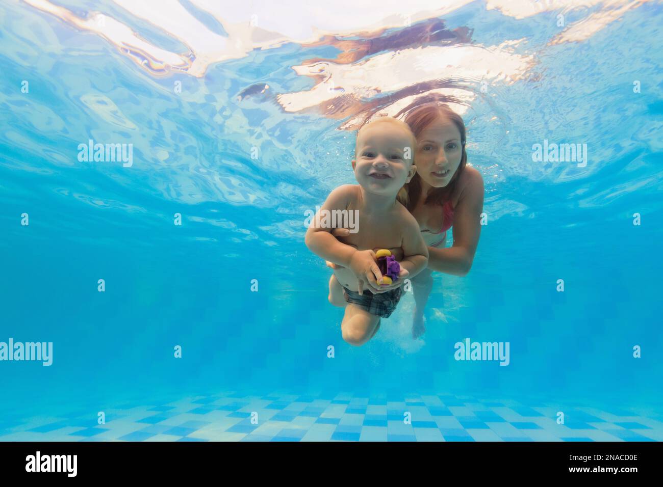 Happy family mother with baby boy swimming and diving underwater with