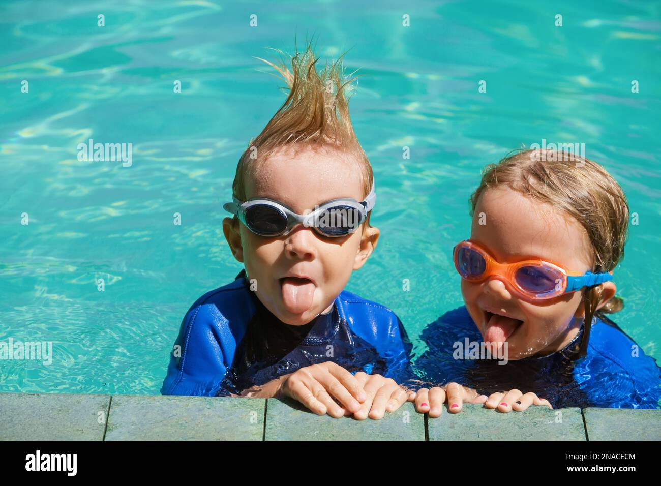 Happy children in wetsuits and goggles learn to swim, have fun at