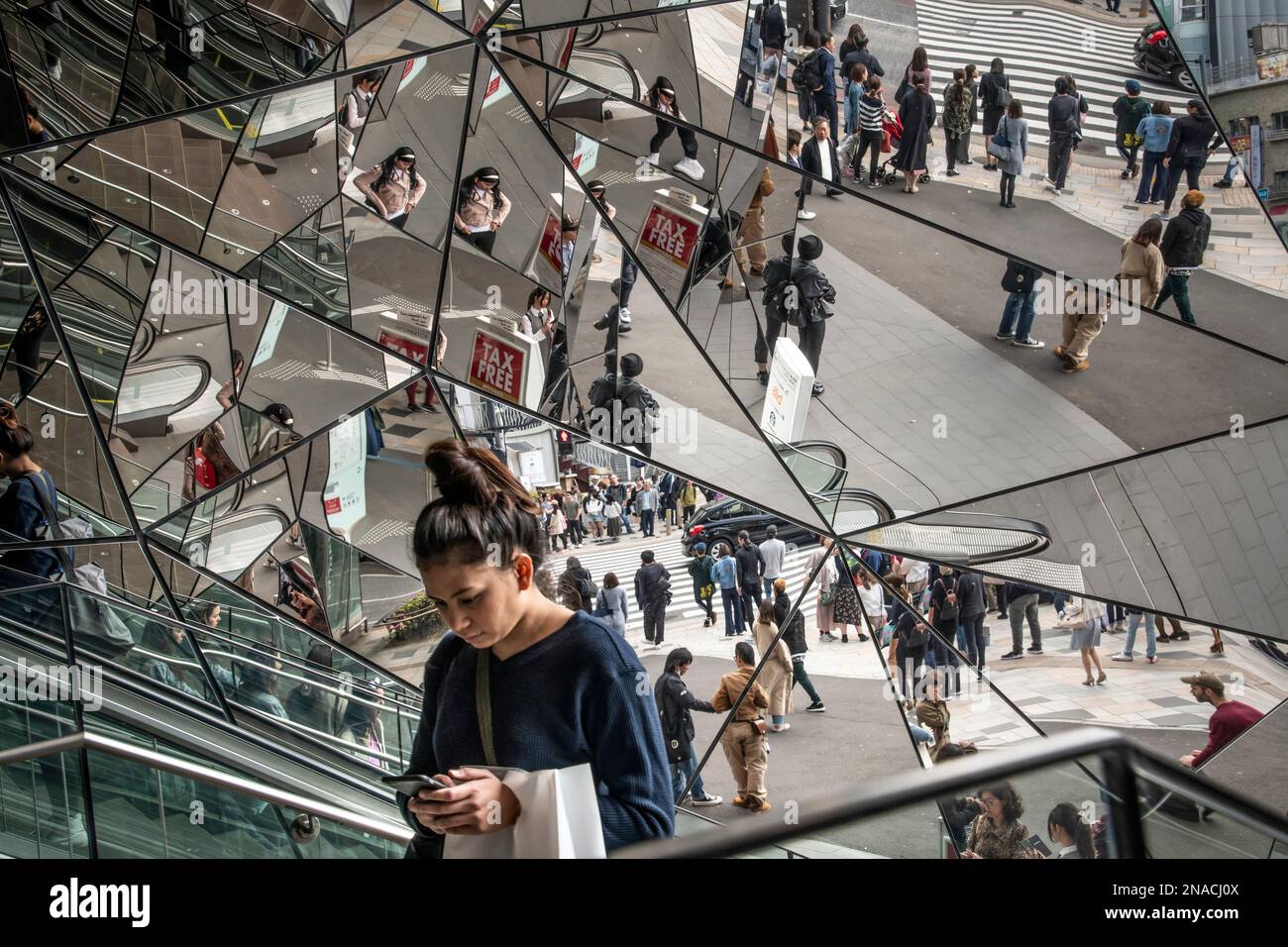 Woman on an escalator surrounded by multiiple mirrors in the Roppongi Hills area of Tokyo. Stock Photo
