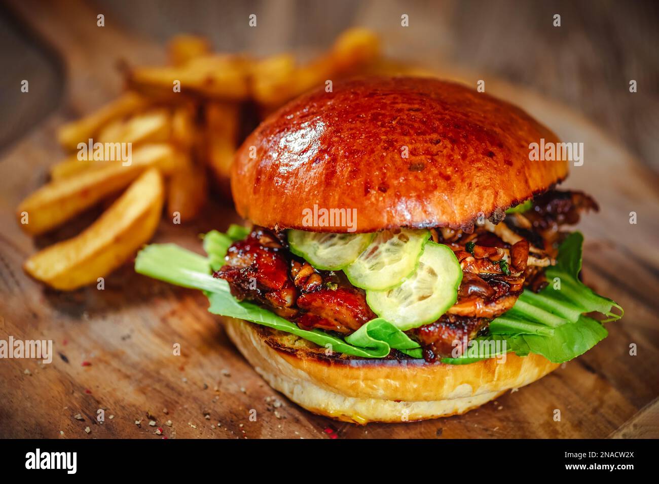 burger with pork ribs, served with cucumber and dipped teriyaki sauce on a wooden cutting board Stock Photo