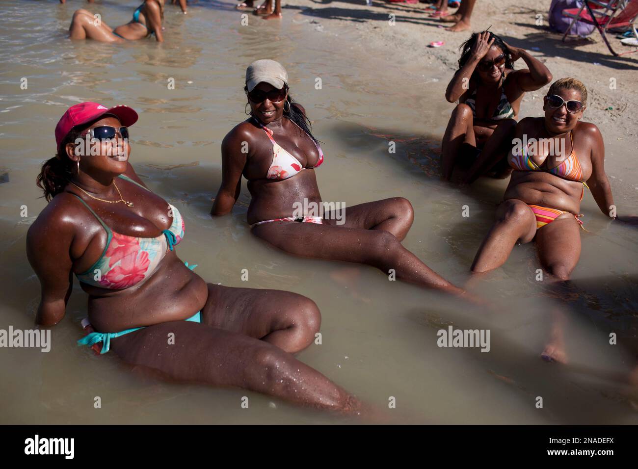 In this photo taken Jan. 24, 2012, women sunbathe at the artificial lake  Piscinao de Ramos in Rio de Janeiro, Brazil. A growing number of bikini  manufacturers have woken up to Brazil's