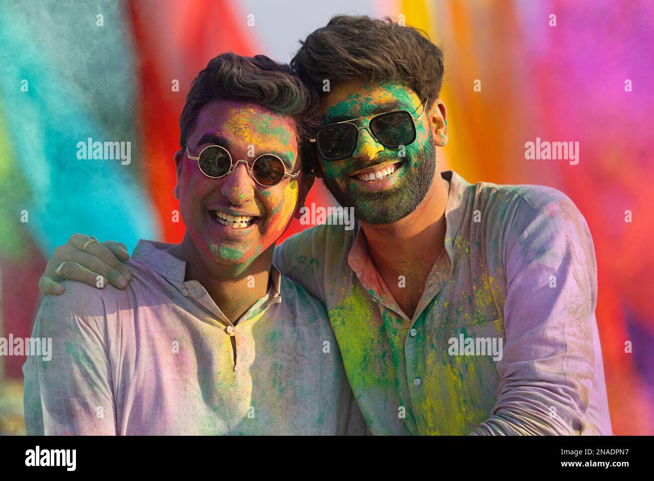 close-up portrait of smiling young men with colourful face and sunglass on holi Stock Photo