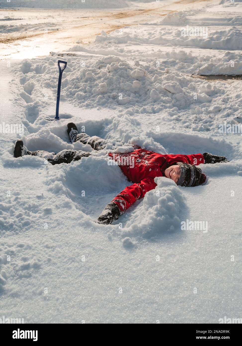 Happy boy laying in snow making snow angel on winter day. Stock Photo