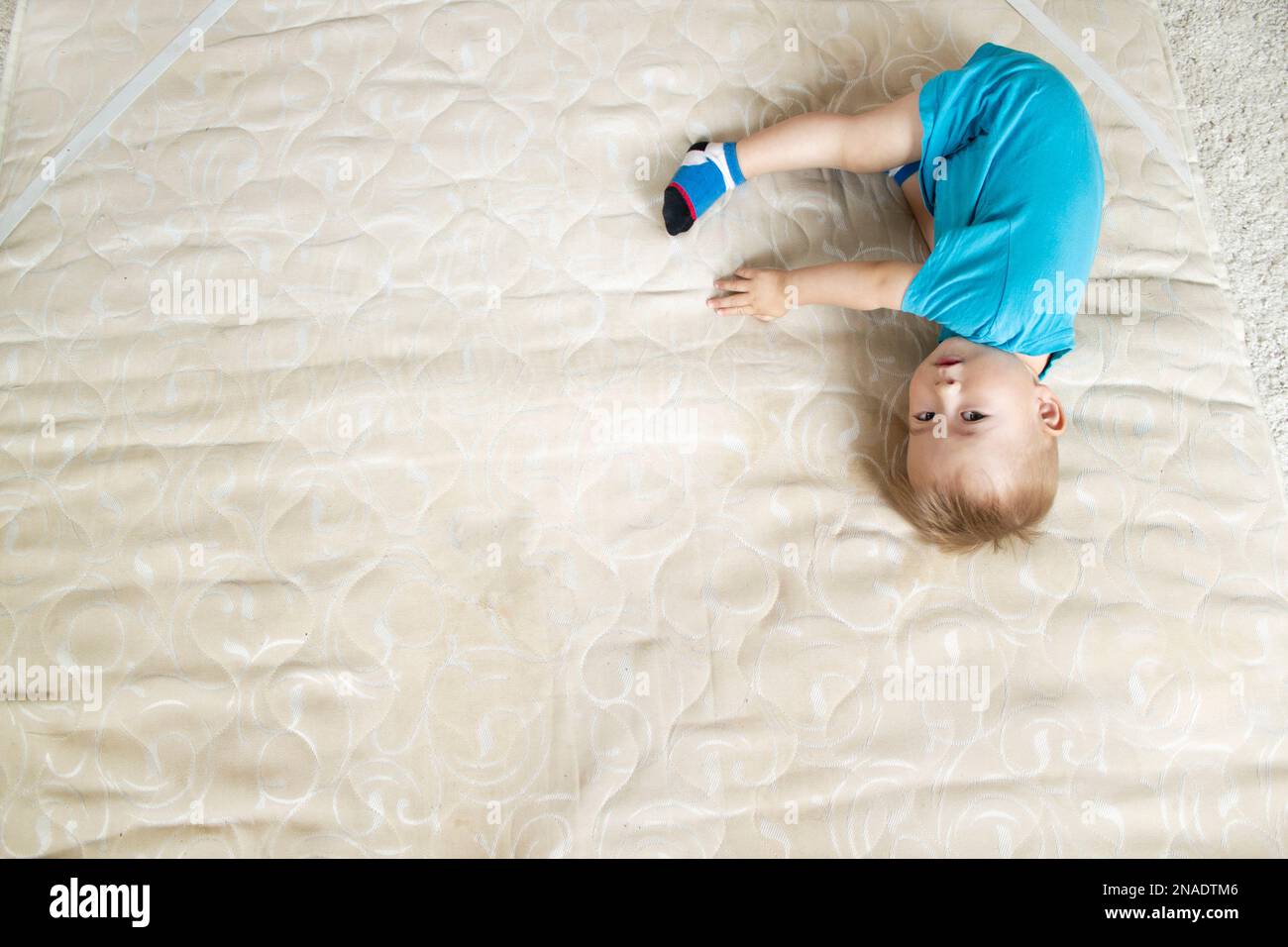 Baby boy lies on mattress and look at camera Stock Photo