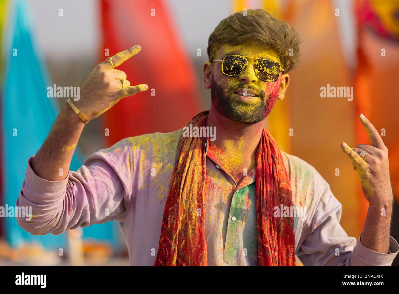 portrait of smiling young man with colourful face and sunglass on holi Stock Photo