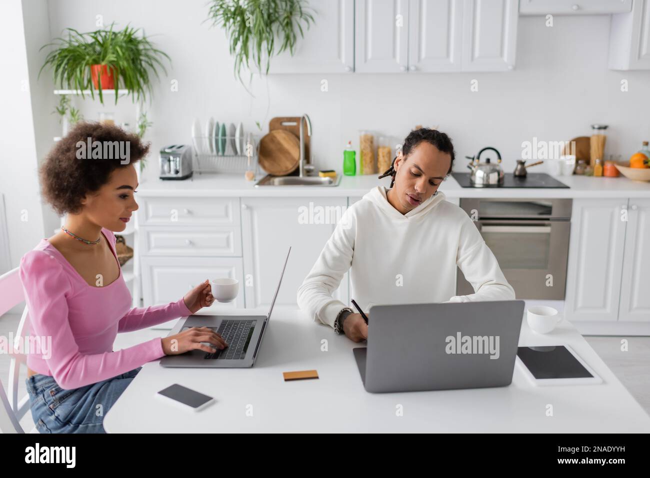 African american freelancers using laptops in kitchen Stock Photo