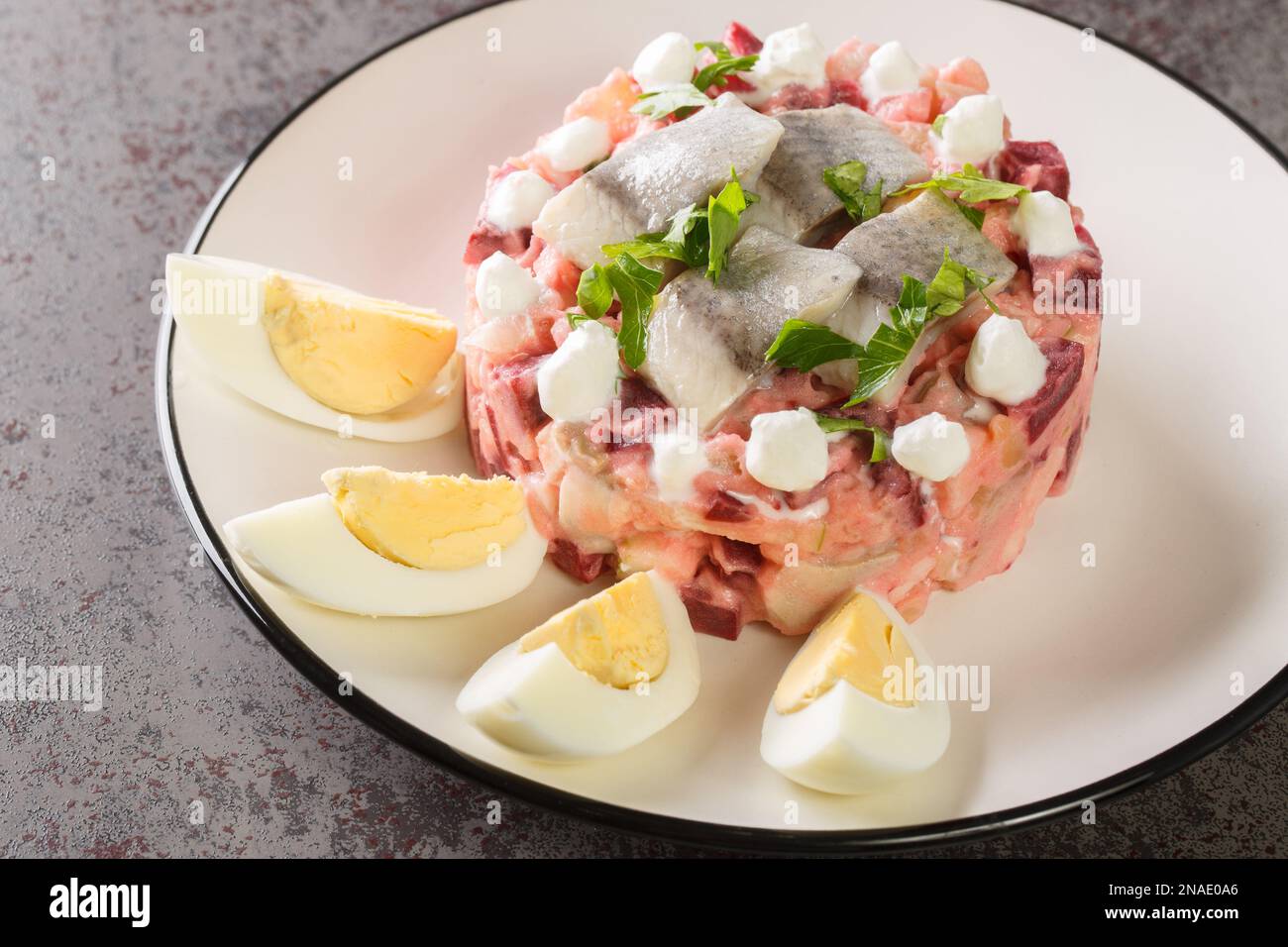 Herring salad with beets, apple, potatoes and onions closeup in a