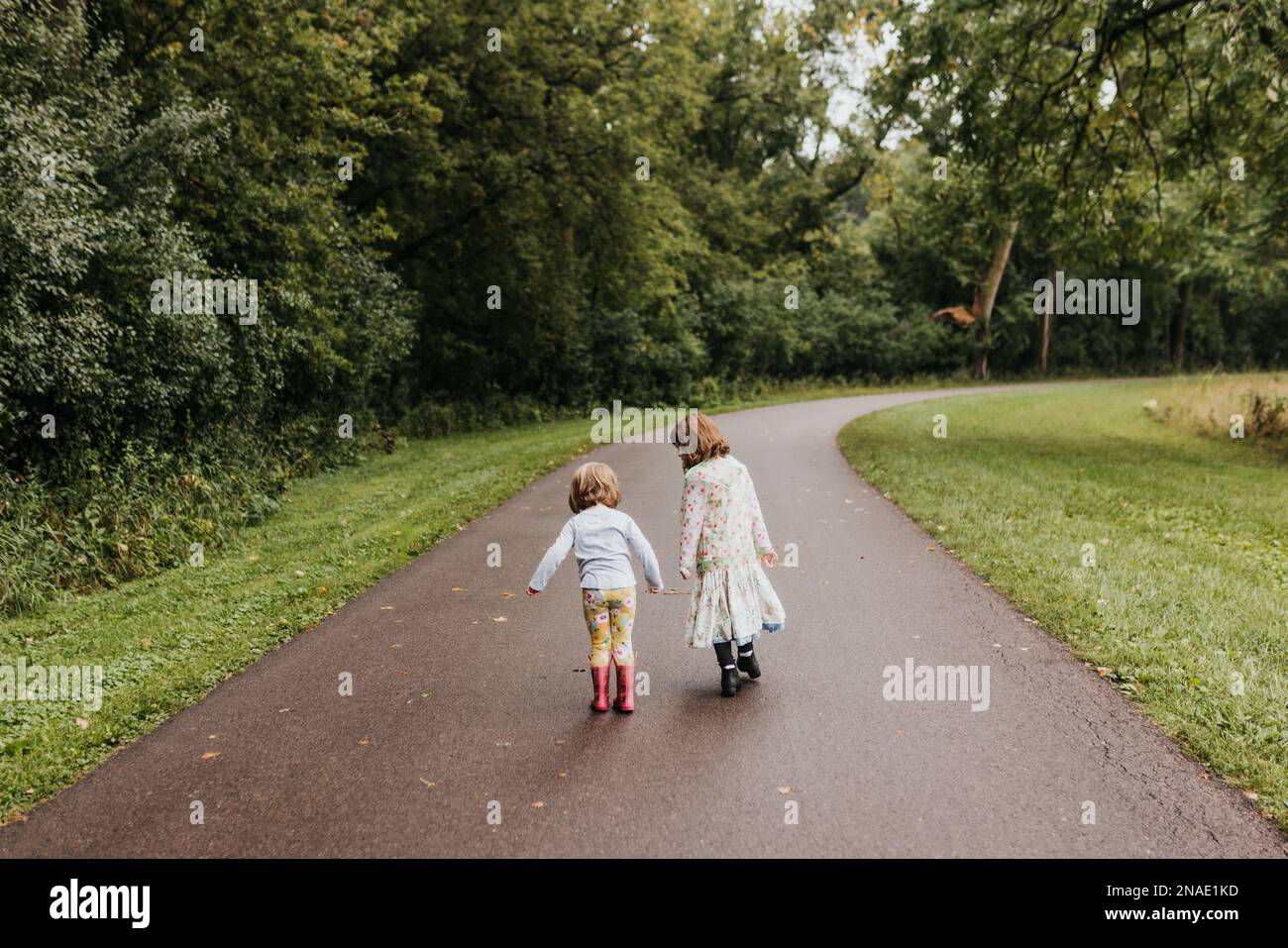 wide shot of sisters walking together outside on park trail Stock Photo ...