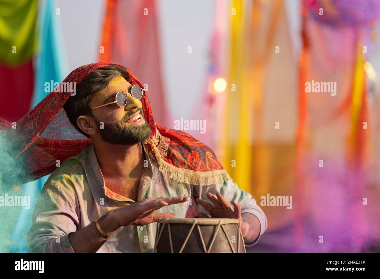 man playing on a dhol with colored face during holi color festival Stock Photo