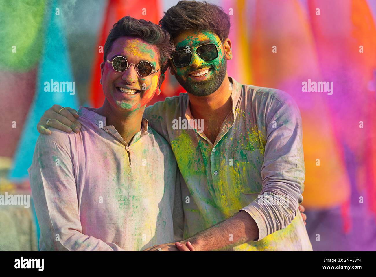 close-up portrait of smiling young men with colourful face and sunglass on holi Stock Photo