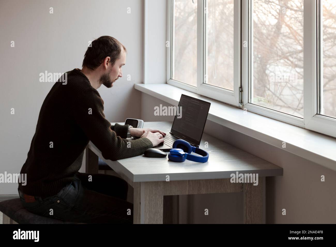 Young man working on laptop at home sitting on table Stock Photo