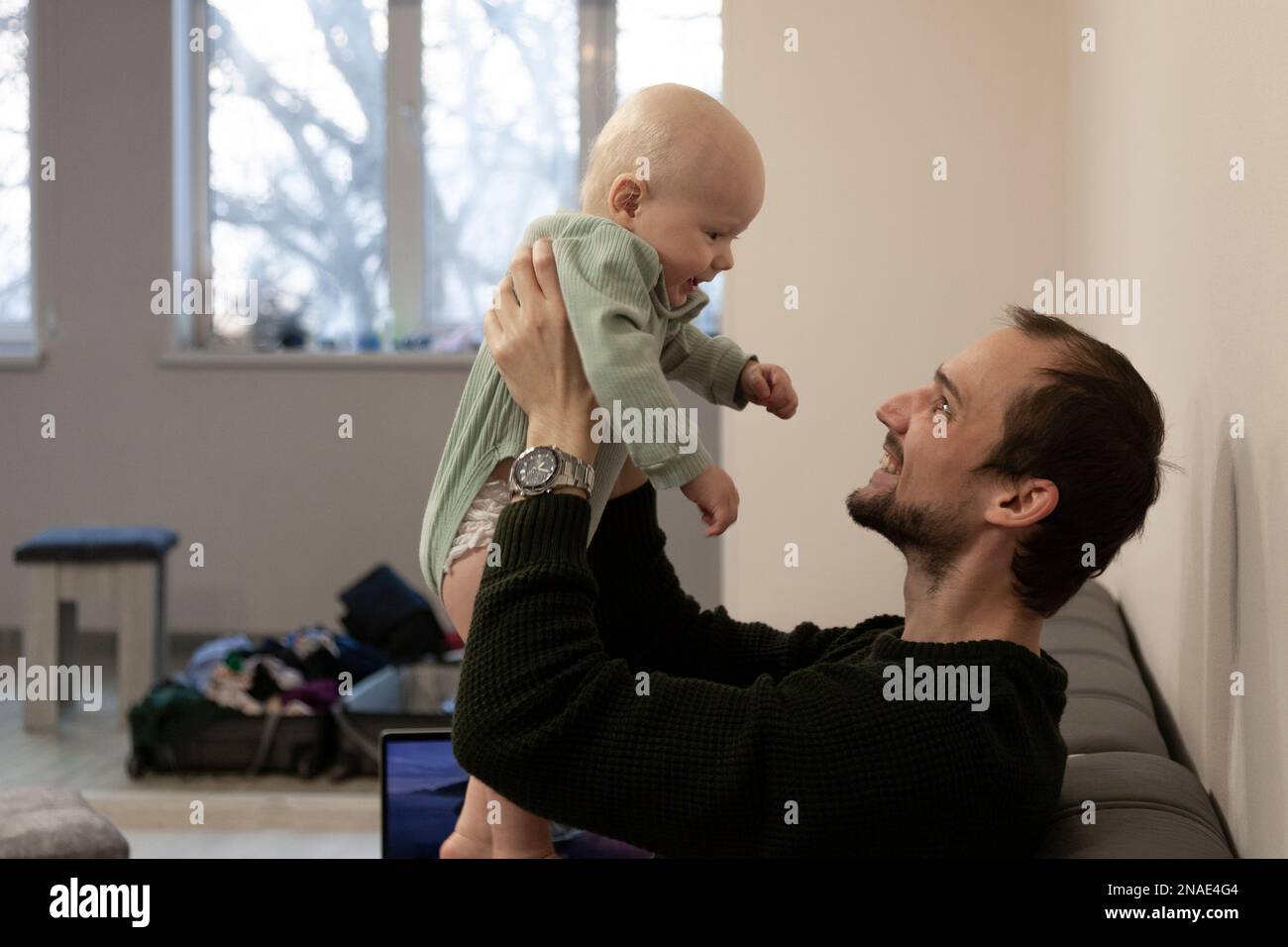 Dad holds the baby in front of him in his arms and smiles Stock Photo