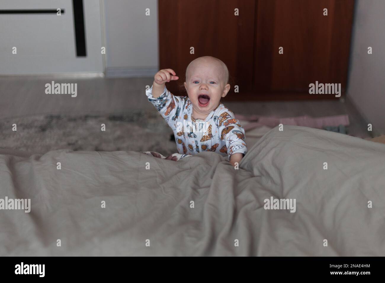 Ð¡hild screaming with raised hand near bed Stock Photo