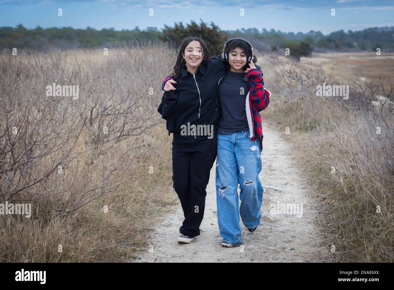 biracial sisters walking while embracing and smiling Stock Photo