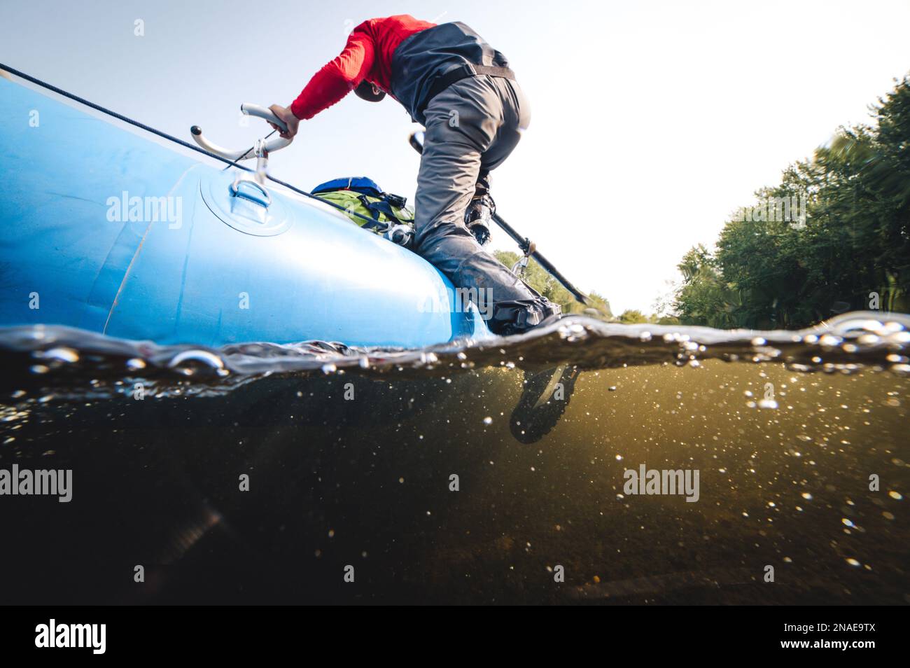 Man climbing out of water onto drift boat Stock Photo