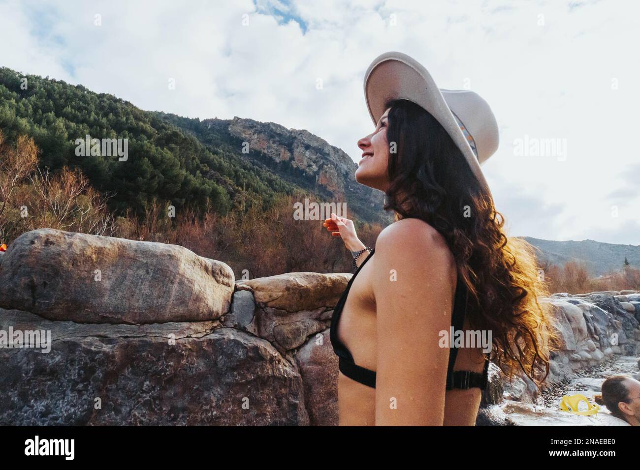 woman with swimsuit and hat in natural hot springs against nature Stock Photo