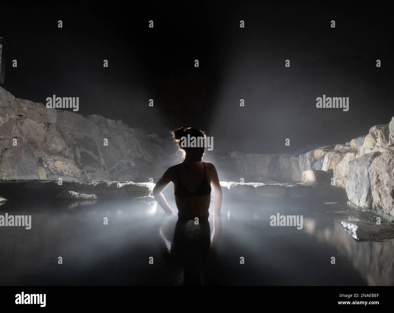 woman in natural hot springs at night with steam and backlight Stock Photo