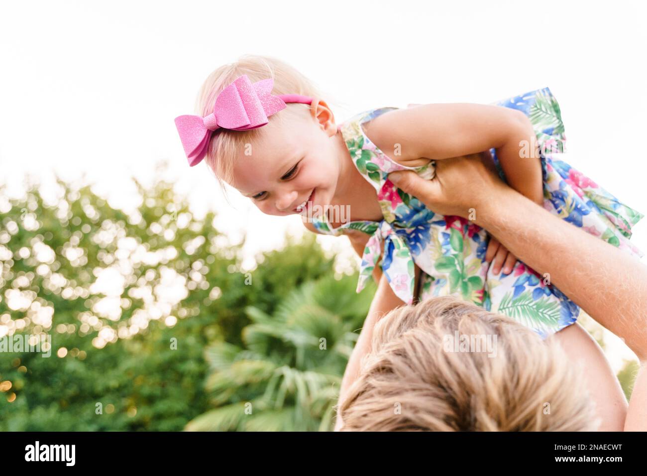 Dad throws his baby girl in his arms in the summer outdoors Stock Photo