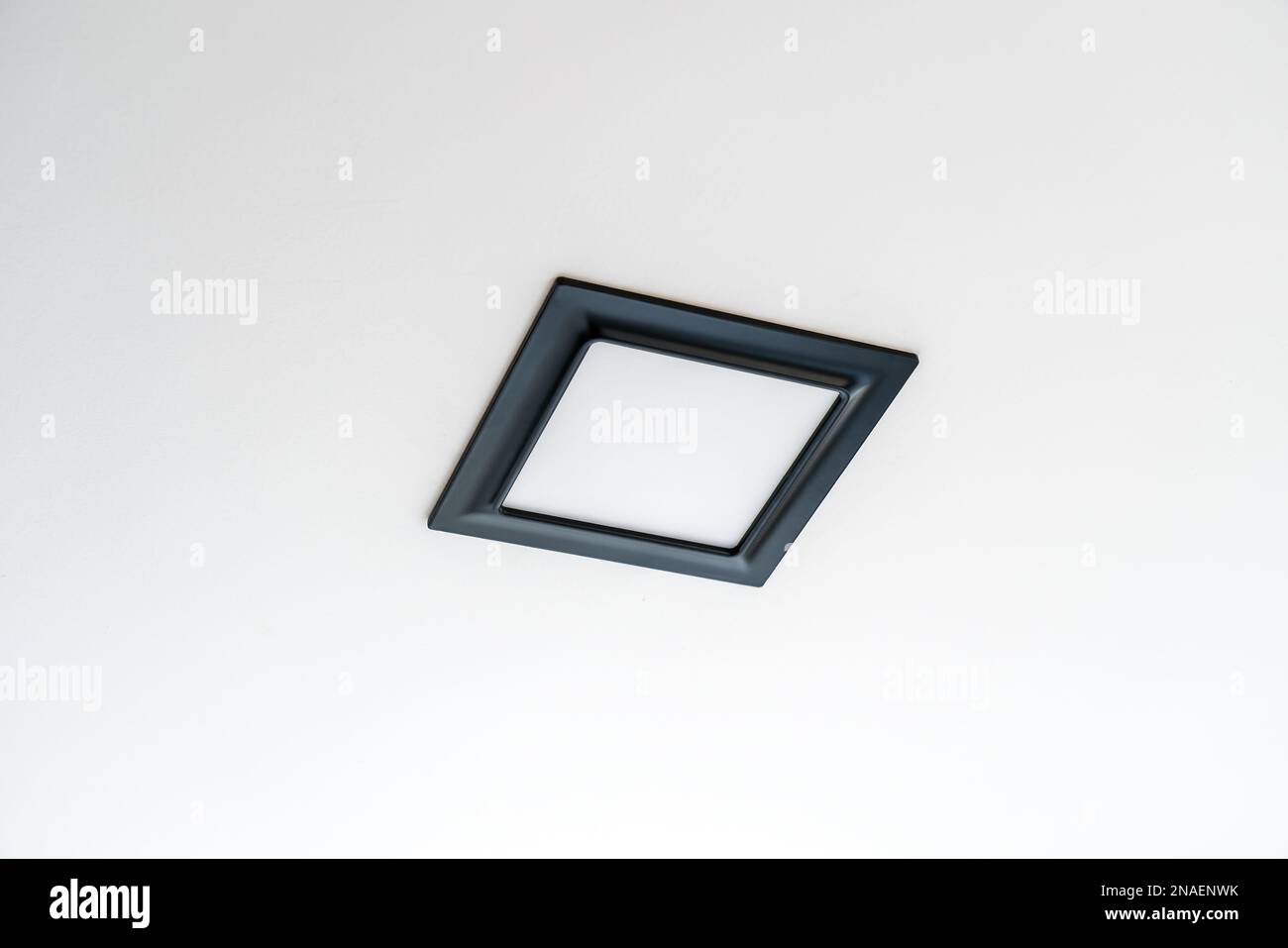 Black plastic rectangular LED lamp isolated on a white ceiling. Stock Photo