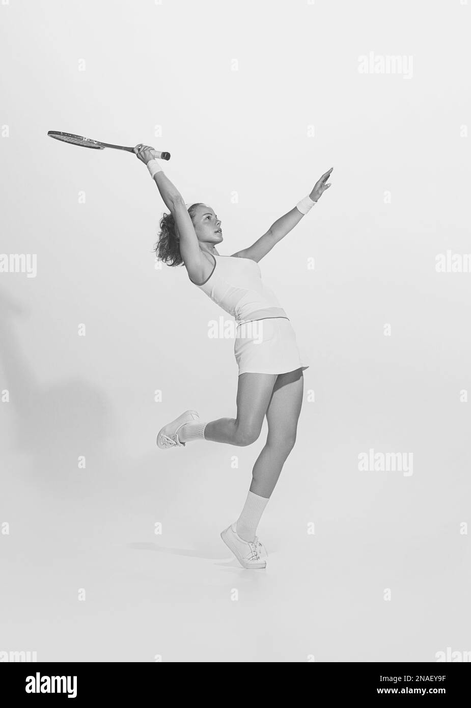 Black and white portrait of young sportive woman in white uniform playing badminton. Retro vintage sport, fashion, art Stock Photo