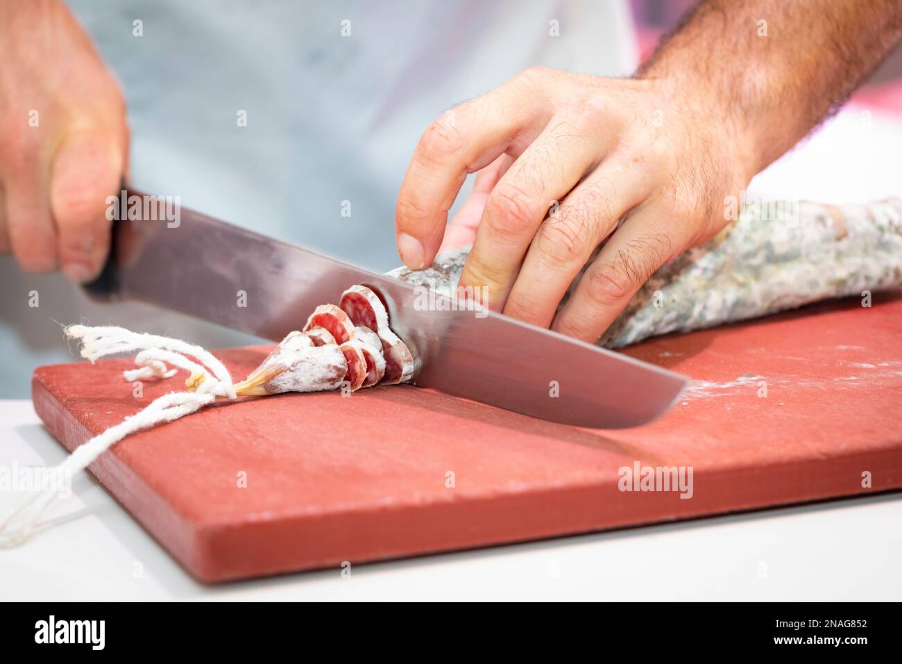 Man hands slicing llonganissa (cured & dried pork sausage) Stock Photo