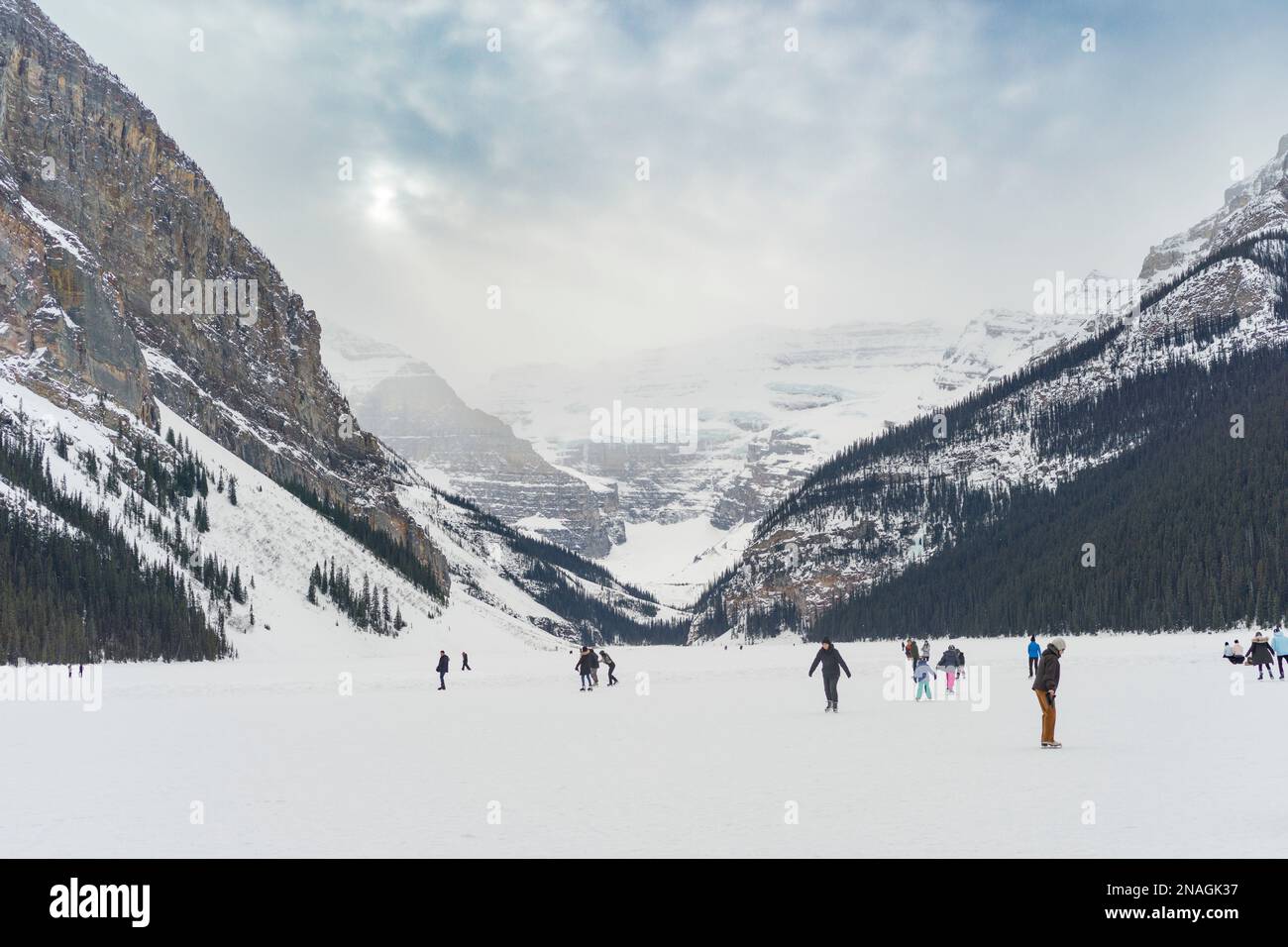 Tourists ice skating and enjoying a frozen Lake Louise in winter, Banff