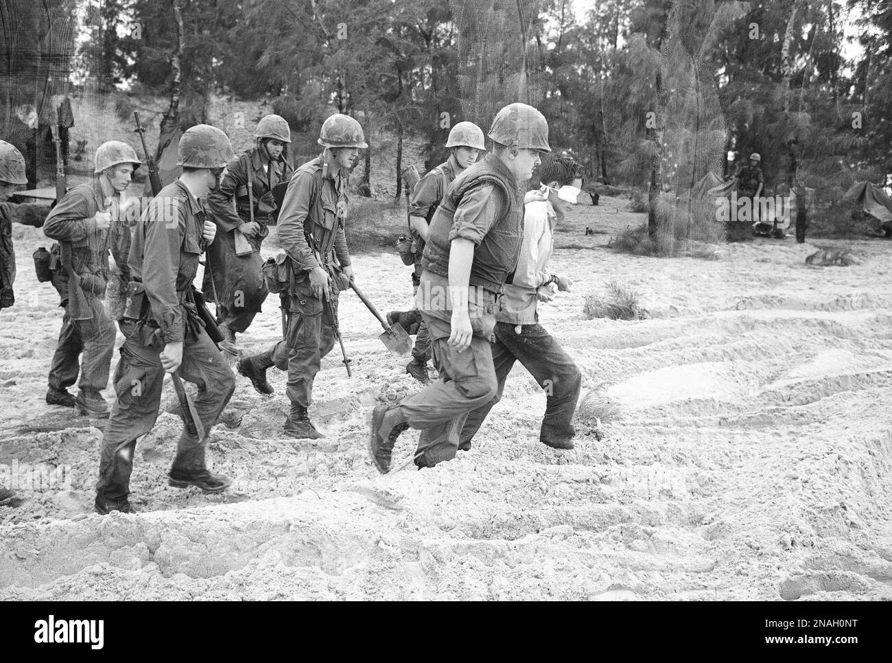 Troops marching on the beach leading a blindfolded prisoner during the ...