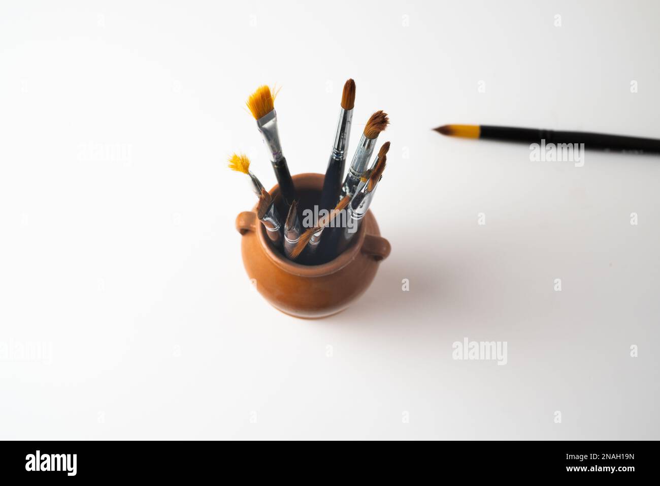 top view earthenware jar with brushes isolated on a white background