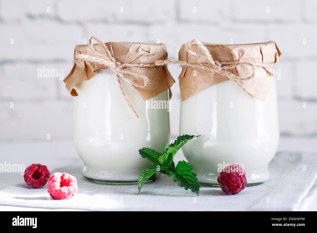 Organic probiotic milk kefir drink or yogurt in glass containers, with raspberry, on the white grey background. Gut health. Probiotic cold fermented d Stock Photo