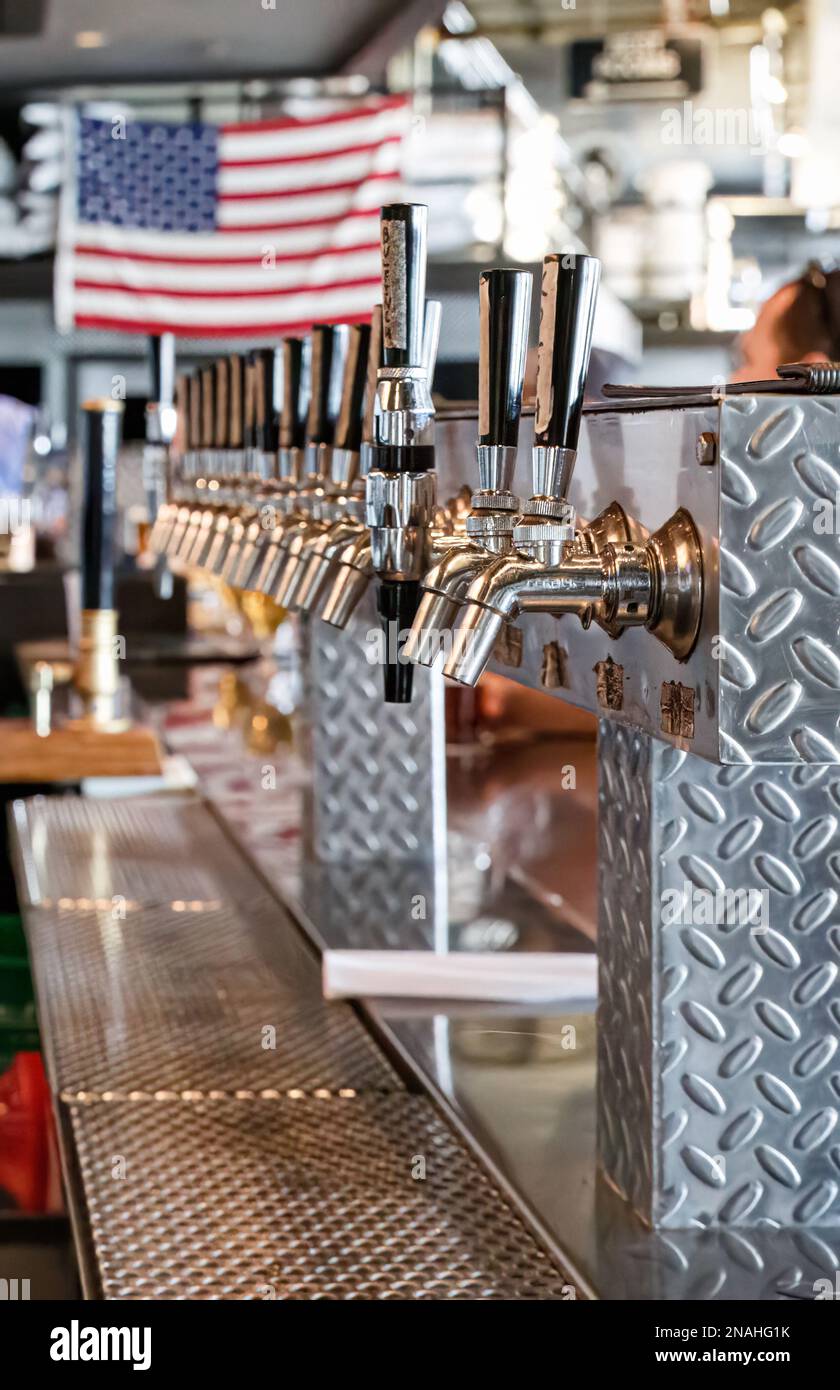 Industrial bar with row of beer taps and US American flag Stock Photo
