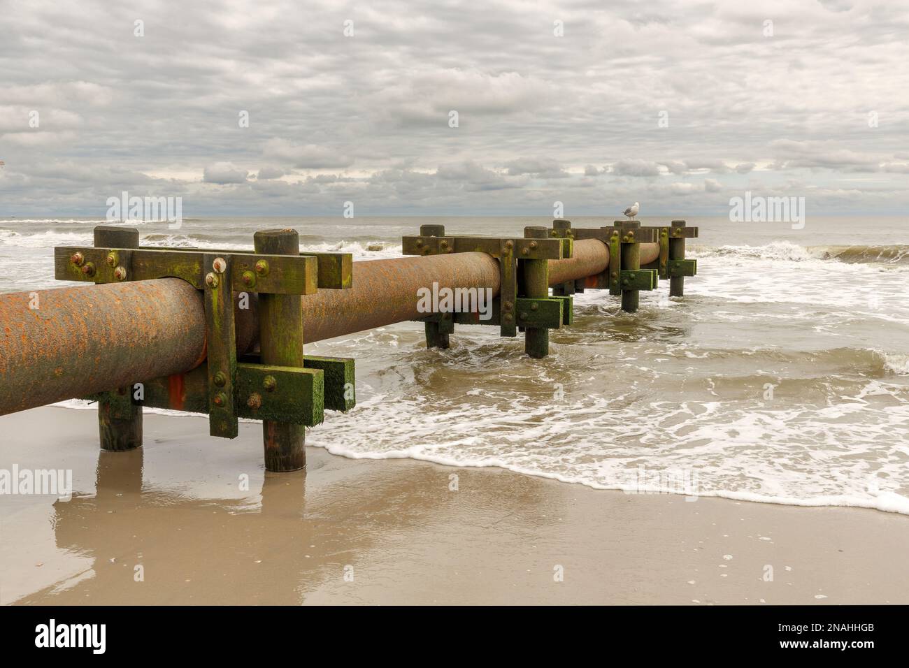 Industrial water pump draining into ocean at beach front Stock Photo