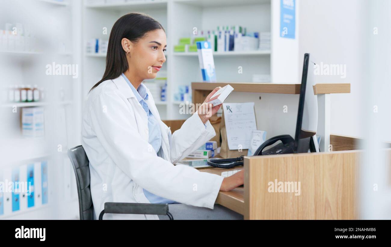 Young pharmacist working on computer at a pharmacy counter. Woman using technology to access