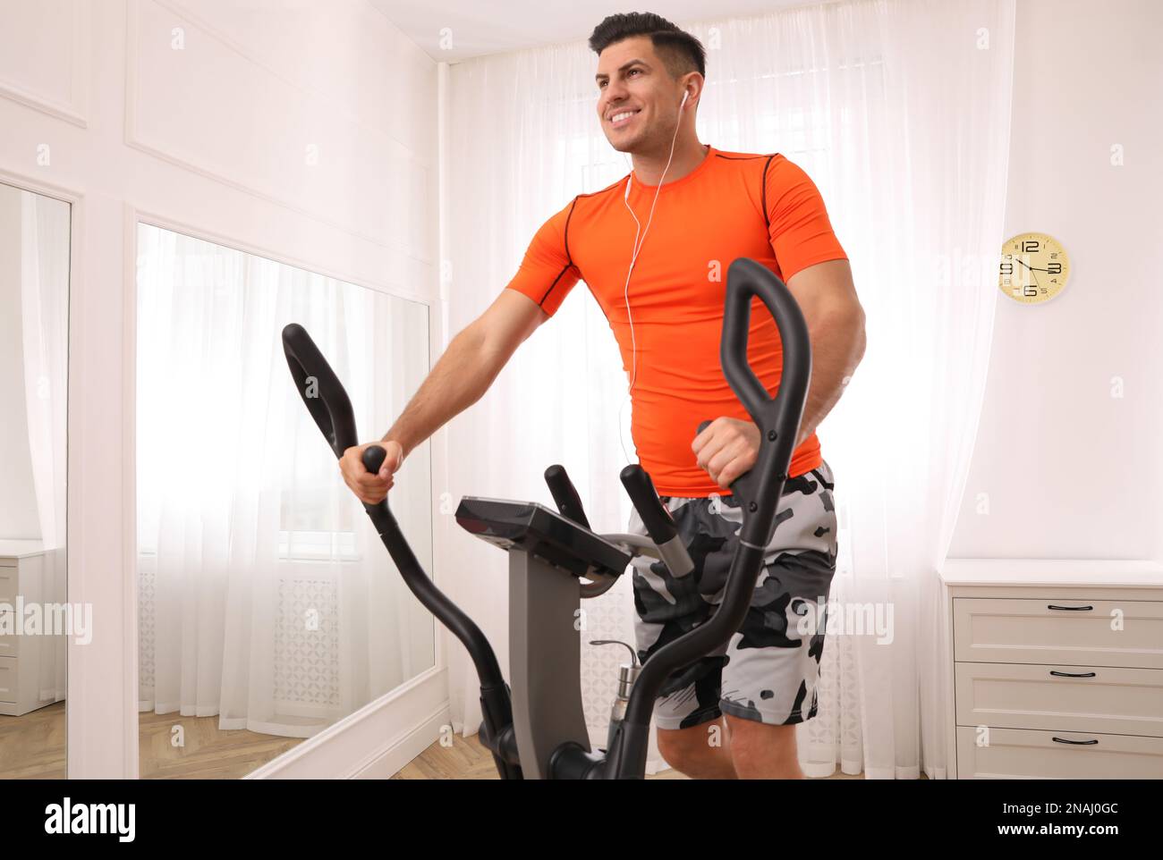 Using Elliptical Machines Man using modern elliptical machine at home Stock Photo - Alamy