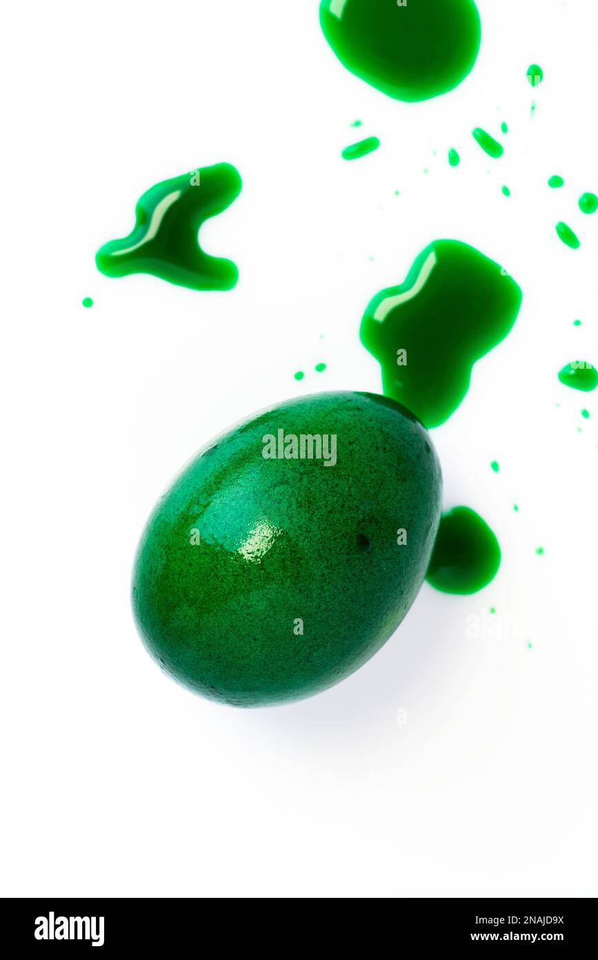 Green easter egg and liquid food coloring on white background. Close up shot. Stock Photo