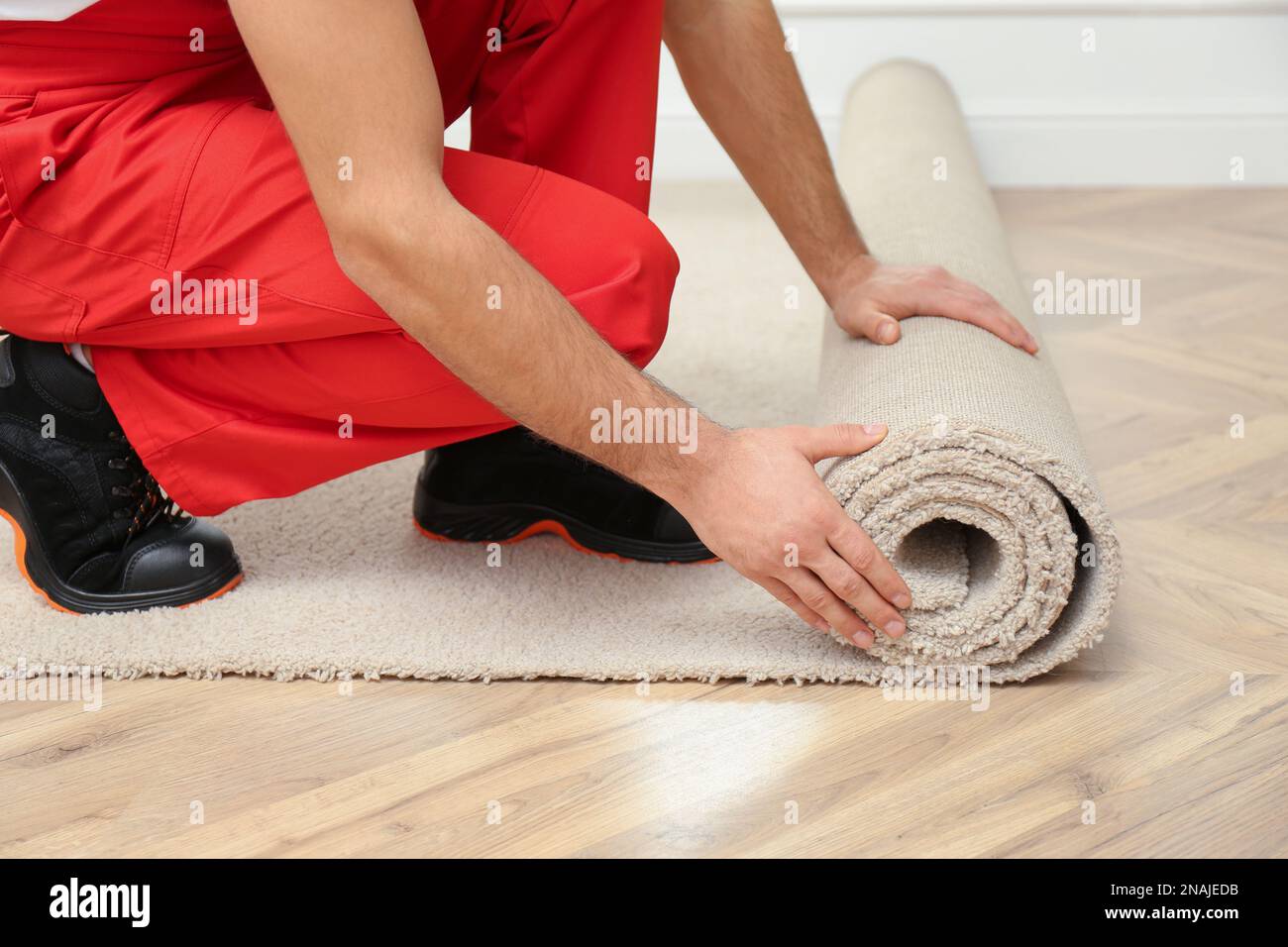 Worker rolling out new carpet flooring indoors, closeup Stock Photo