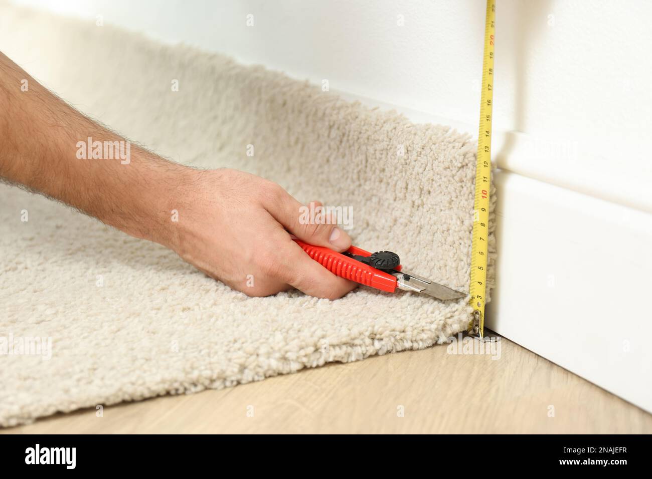 Worker with cutter knife and measuring tape installing new carpet indoors,  closeup Stock Photo - Alamy