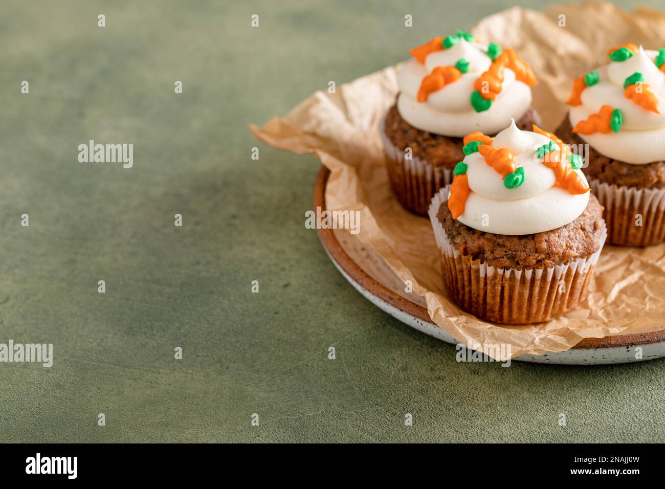 Carrot cupcakes with cream cheese frosting decorated with tiny frosting carrots, Easter dessert idea Stock Photo