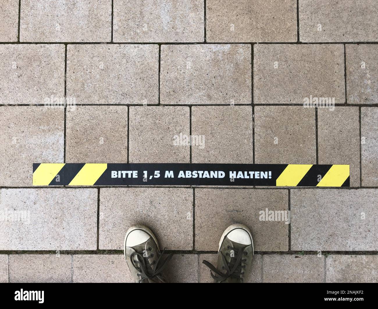Bitte 1, 5 m Abstand halten - German for Please keep 1.5 m distance - line marking on sidewalk - social distancing in Germany Stock Photo