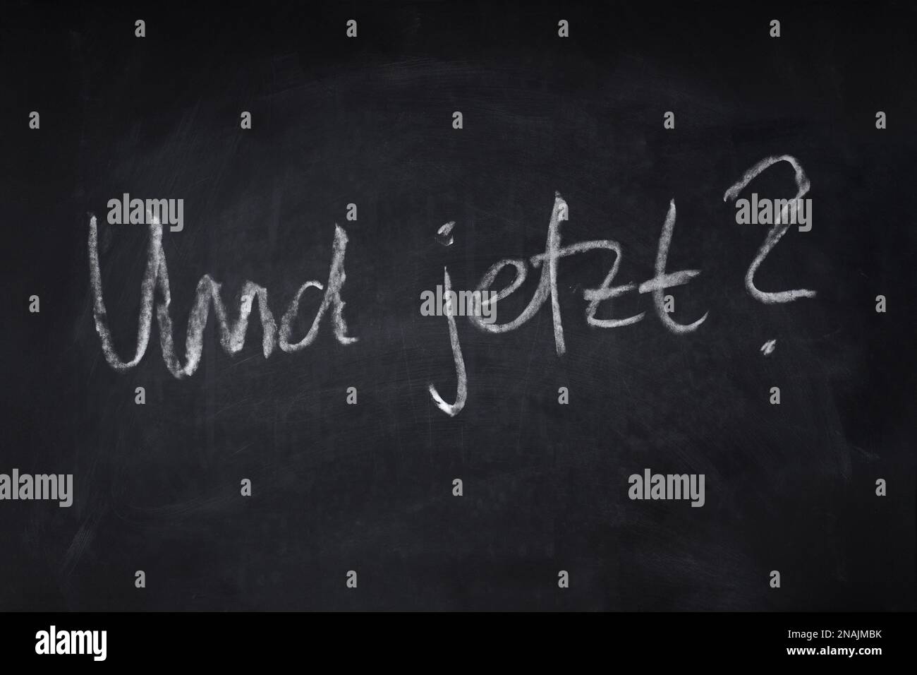 und jetzt translates as what now in German - handwritten question on chalkboard - uncertainty, angst and anxiety about the future concept Stock Photo