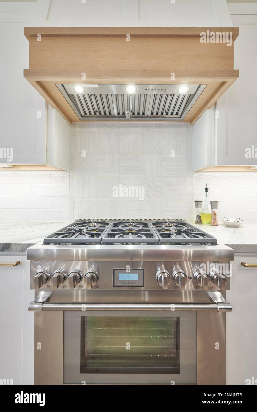 Stainless gas range and wood range hood in modern kitchen Stock Photo